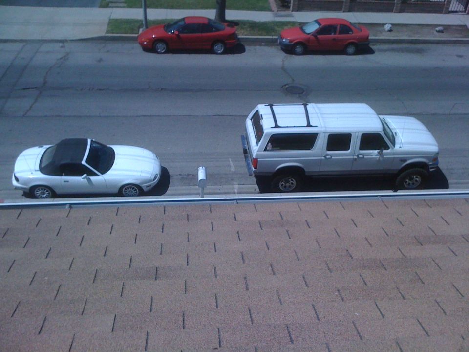 White convertible sports car parked next to a white SUV on a street