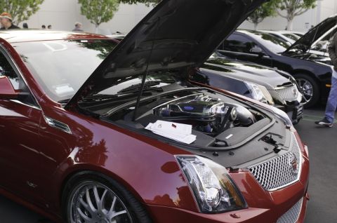 2006 Cadillac STS - A red Cadillac sedan is displayed with its hood open, revealing the engine, alongside other vehicles.