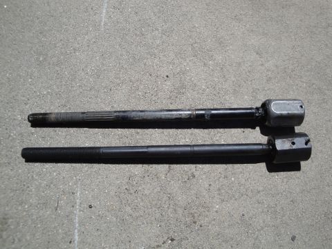 1995 Ford Taurus - Comparison of a used tie rod end with a new one, both resting on a concrete surface.