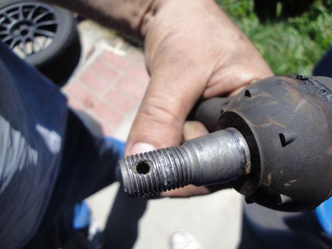1995 Ford Taurus - A person is holding a worn tie rod end, a critical component of a vehicle's steering system.