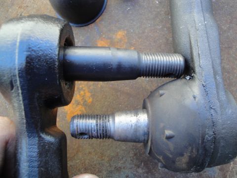1995 Ford Taurus - Comparison of two tie rod ends, one appearing new and black, the other showing a rubber boot and metal stud.