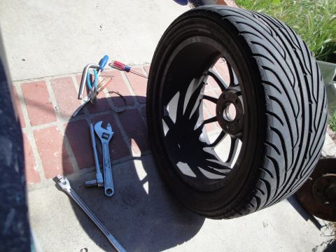 1995 Ford Taurus - Tools are laid out on the pavement next to a car wheel, suggesting a repair or maintenance task is underway.