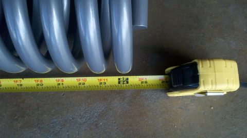 1996 Ford Bronco - Coil spring measured with a tape measure, indicating its size.