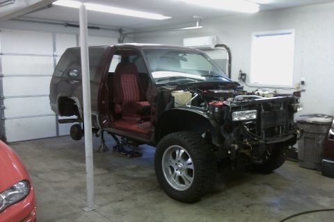 1994 Chevrolet Blazer - Maroon Chevrolet S-10 Blazer in a garage with its front end removed for repairs.