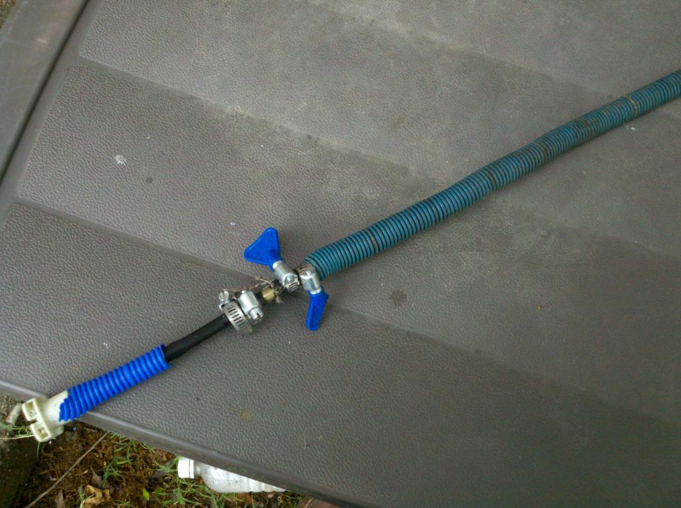 Blue braided automotive hose with shut-off valve lying on a plastic surface