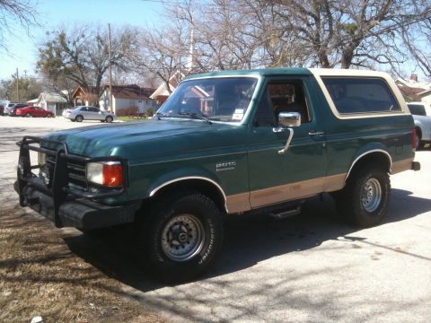 1989 Ford Bronco - This 1989 Ford Bronco features a two-tone paint scheme with a tan removable top and a prominent front brush guard.