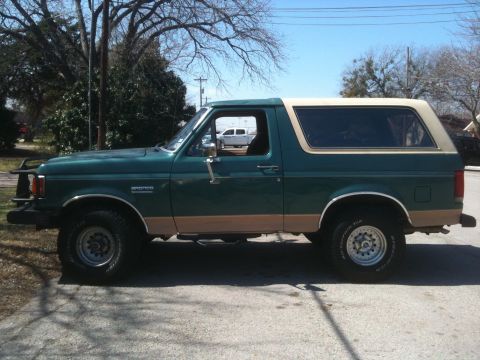 1989 Ford Bronco - Side view of a green 1989 Ford Bronco, tan trim and off-road tires.