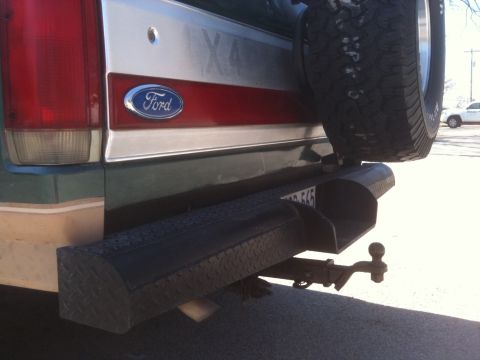 1989 Ford Bronco - Rear view of a green Ford Bronco with a spare tire and tow hitch visible.