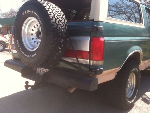 1989 Ford Bronco - This 1989 Ford Bronco features a rear-mounted spare tire and a green exterior with woodgrain trim.