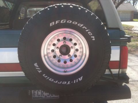 1989 Ford Bronco - Rear view of an SUV showing a mounted spare tire and part of the tailgate.
