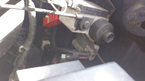 1994 Ford Bronco - Tight, slightly blurred shot down into a truck's under-dash area showing a metal steering-column bracket with a rubber grommet boot, a red…