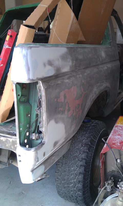 1995 Ford Bronco - The rear quarter panel of a vehicle is shown with primer and body filler, indicating it is undergoing repairs or restoration.