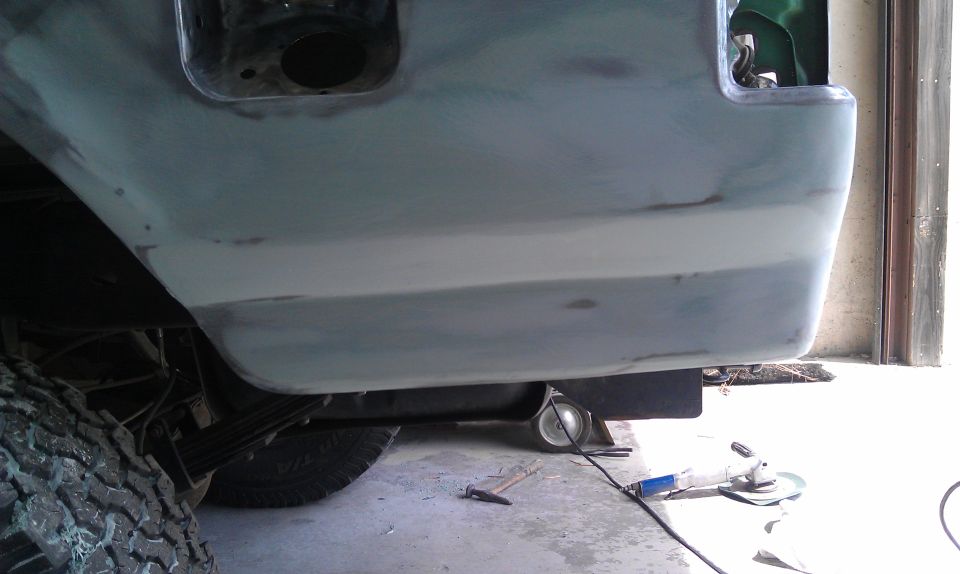 Truck lower rear quarter panel in primer with filler work, mud tire and leaf spring below