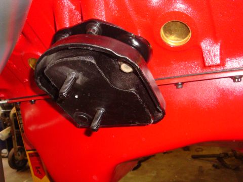 1989 Ford Bronco - Close-up view of an engine mount attached to a red engine block, with a brass plug in the background.