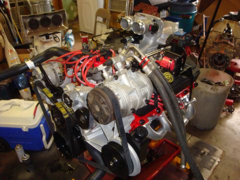 1989 Ford Bronco - Engine assembly with a prominent supercharger and red spark plug wires, likely undergoing preparation.