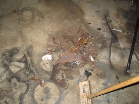 1979 Ford Bronco - Pile of rusty metal parts and debris on a concrete floor, possibly from a vehicle.