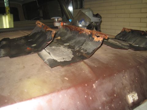 1979 Ford Bronco - Several pieces of heavily rusted metal are laid out on the hood of a vehicle.