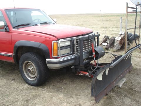 1994 GMC Sierra 3500 - A red 1994 GMC Sierra 3500 pickup truck is equipped with a snow plow and parked outdoors.