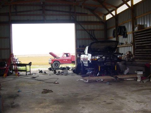 1992 Ford Bronco - A 1992 Ford F-250 truck is undergoing repairs inside a garage, with a red Ford truck visible outside.