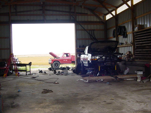 1992 Ford F-250 truck with hood open, front view, on lift inside garage