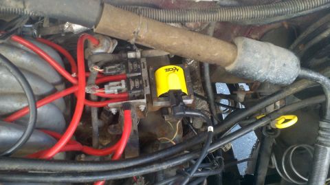 1989 Ford Bronco - Close-up view of an engine bay red spark plug wires and a yellow ACCEL ignition coil.