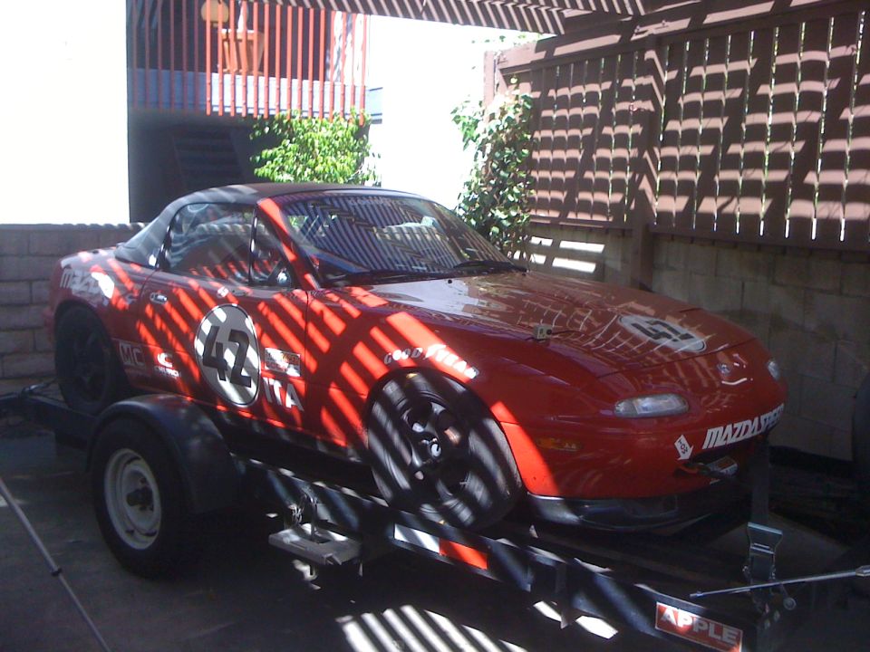 Red 1991 Mazda Miata race car with number 42 on trailer. MazdaSpeed decal on front bumper