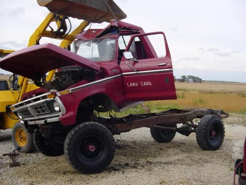 1992 Ford Bronco - This heavily damaged red pickup truck, possibly a 1977 Ford F-250, is being lifted by a yellow crane.