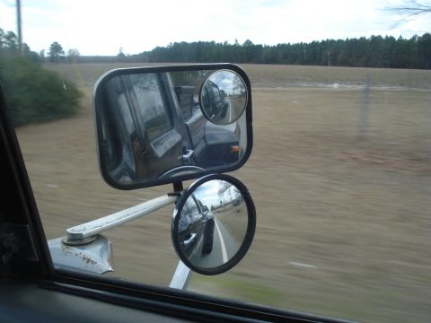 1989 Ford F-250 - View from a truck's side mirror, showing the road and surrounding landscape.