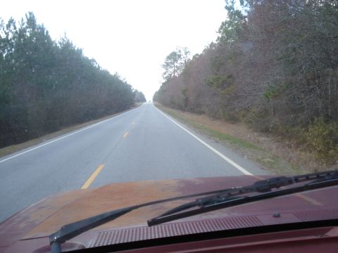 1989 Ford F-250 - Driving down a rural road, showing the hood and windshield of the vehicle.