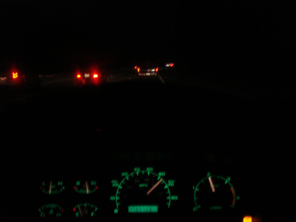1989 Ford F-250 interior dashboard with glowing green gauges and taillights of cars ahead