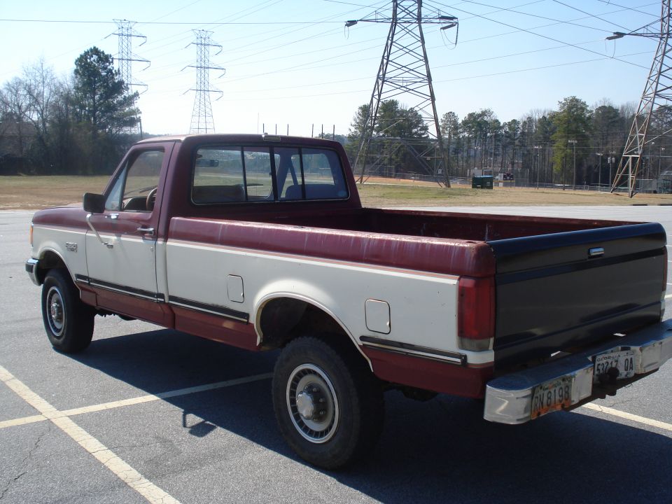 Maroon and white Ford F-250 pickup truck, rear 3/4 view, parked in lot