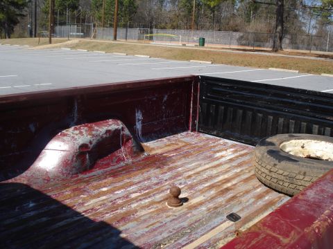 1989 Ford F-250 - Interior view of a red pickup truck bed, showing wear and tear, with a spare tire and hitch ball visible. Matches 1989 Ford F-250 claim.