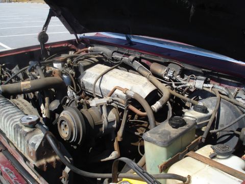 1989 Ford F-250 - The engine bay of a red 1989 Ford F-250, showing various mechanical parts under the hood.