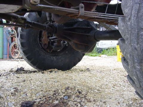 1992 Ford Bronco - Undercarriage view of a vehicle's rear axle and suspension system, with gravel on the ground.
