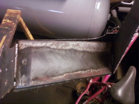 1989 Ford Bronco - A close-up view of a metal box with visible welds and rust, with a pink bicycle frame in the background.