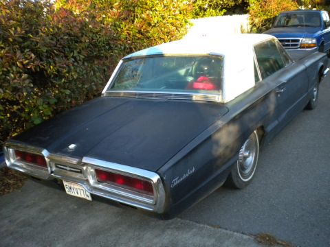 1965 Ford Thunderbird - A classic Ford Thunderbird is parked outdoors, with a blue pickup truck visible in the background.