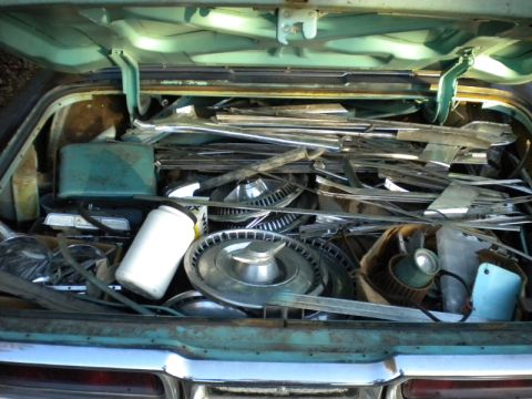 1965 Ford Thunderbird - The trunk of a 1965 Ford Thunderbird is packed with various automotive parts and trim pieces.