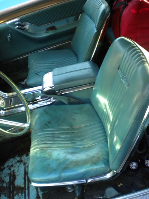 1965 Ford Thunderbird - The interior of a 1965 Ford Thunderbird features teal bucket seats and a prominent center console.
