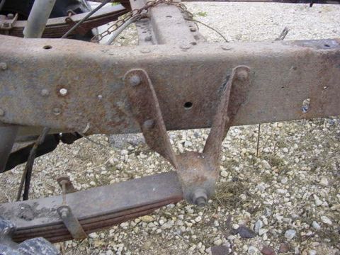 1992 Ford Bronco - Close-up of a heavily rusted truck frame and leaf spring suspension system.