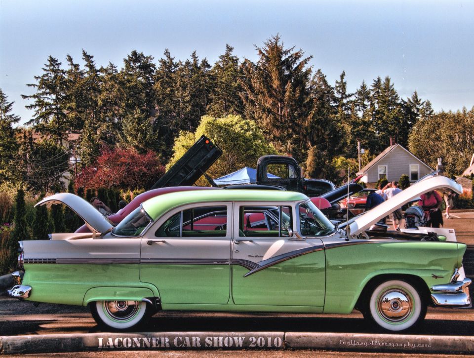 Two-tone green/white 1950s Ford sedan, side view, hood and trunk open at car show