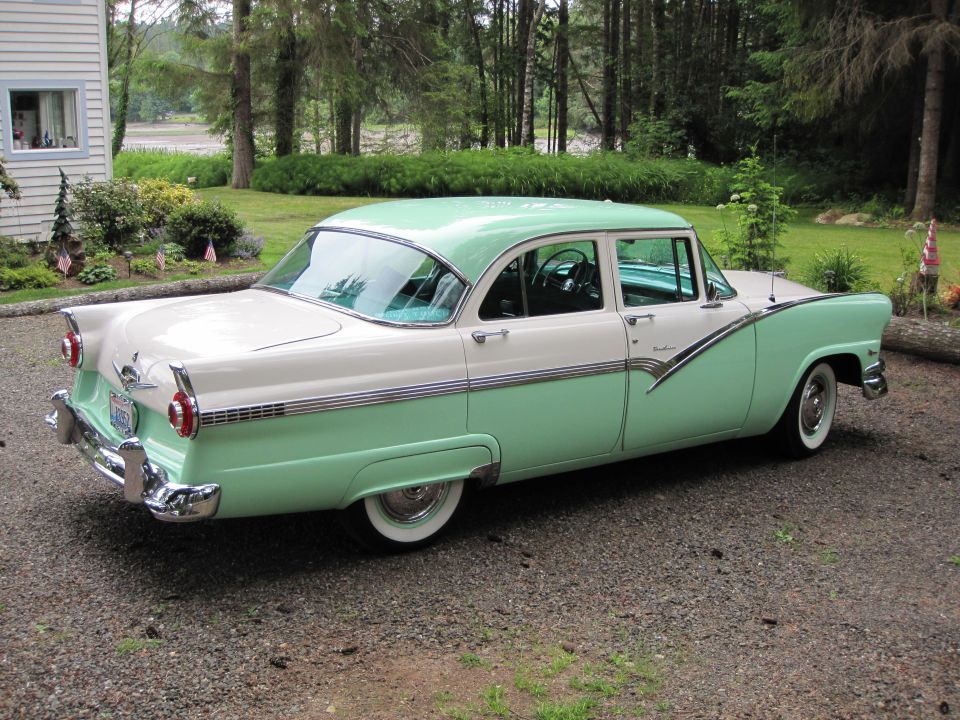 Two-tone green and white 1950s sedan, rear-three-quarter on gravel