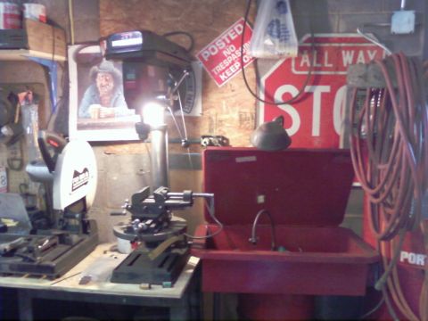 1989 Ford Bronco - A cluttered garage workshop displays various tools and equipment, including a drill press and a parts washer.
