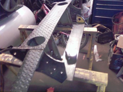1989 Ford Bronco - Unidentified metal part with diamond plate texture, possibly a frame component, is supported by sawhorses in a workshop.