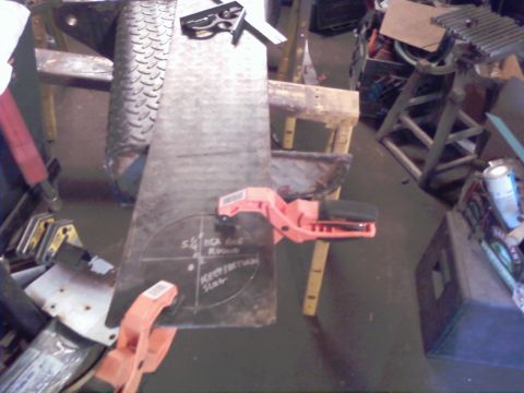 1989 Ford Bronco - Metal plate marked for cutting, secured with clamps in a workshop setting.