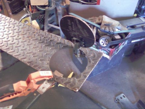 1989 Ford Bronco - A close-up view of a metal grinding wheel and a tool clamped to a diamond plate surface in a workshop setting.