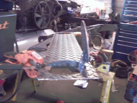 1989 Ford Bronco - A diamond plate metal part is shown on a workbench in a cluttered garage setting.
