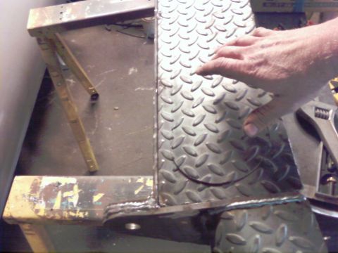 1989 Ford Bronco - A close-up view of diamond plate metal attached to a metal frame, with a hand resting on the surface.
