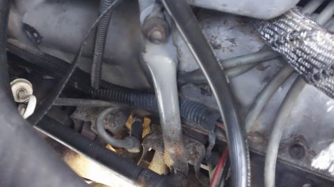 1994 Ford Bronco - Close-up view of engine bay components, including hoses and wiring, with visible rust on a metal bracket.