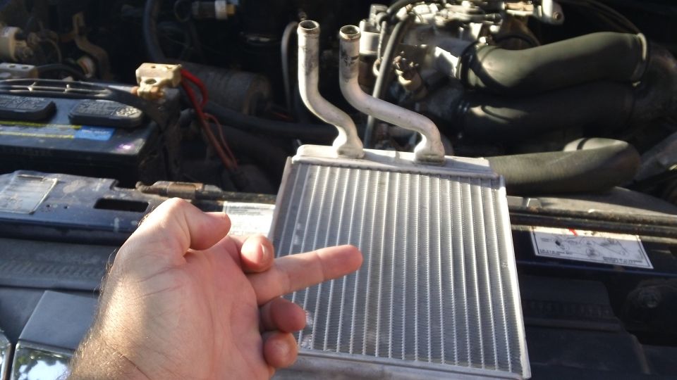 1994 Ford Bronco heater core held in front of engine bay