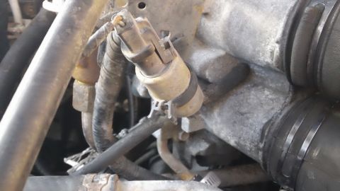 1994 Ford Bronco - This image shows a close-up view of a sensor assembly with attached hoses and wiring within an engine compartment.
